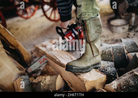 Close-up of a man's working boots. Cutting firewood with a chain Stock Photo
