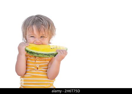 Portrait of cute baby biting yellow watermelon isolated on white background Stock Photo