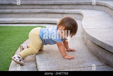 Curious little baby girl watching the camera raising herself up on