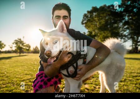 Portrait of a smiling adult Argentinian man posing with his Akita dog in a park Stock Photo