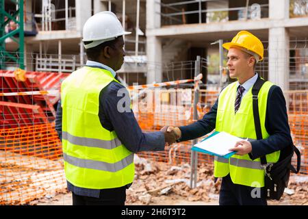 Engineers shaking hands on construction site Stock Photo