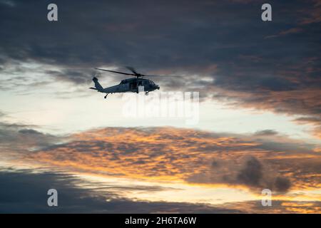 211113-N-FA490-2099 JAVA SEA (Nov. 13, 2021) A MH-60S helicopter assigned to the “Wildcards” of Helicopter Sea Combat (HSC) Squadron 23, flies over the Java Sea during routine operations. HSC 23, part of Destroyer Squadron Seven, is on a rotational deployment in the U.S. 7th Fleet area of operation to enhance interoperability with partners and serve as a ready-response force in support of a free and open Indo-Pacific region. (U.S. Navy photo by Mass Communication Specialist 3rd Class Andrew Langholf/released) Stock Photo