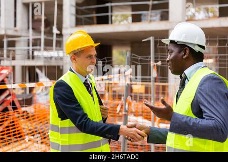 Engineers shaking hands on construction site Stock Photo