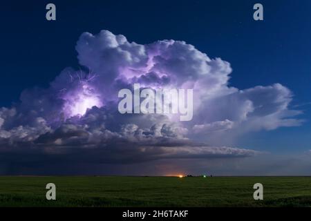 A thunderstorm cumulonimbus cloud is illuminated by lightning near Jetmore, Kansas Stock Photo