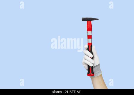 Gloved hands holding hammer construction tools. Work tools on blue background Stock Photo