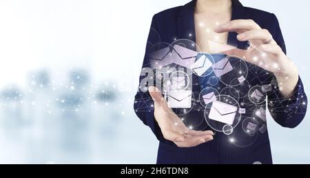 Sending email.Bulk mail. Two hand holding virtual holographic Email and sms icon with light blurred background. Business email concept Stock Photo