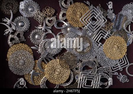 Beautiful finely worked round and oval gold and silver colored pendants for on a chain, cheap jewelry on a market stall with black background Stock Photo