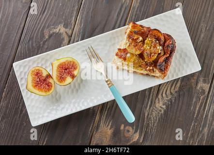 Clafoutis with figs and honey on white plate, on wooden background. French gourmet food. Flat lay Stock Photo
