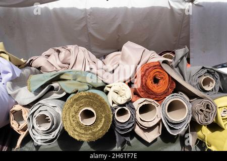 Rolls of textile fabric in all kinds of colors that are offered for sale at the weekly market in Maastricht, the Netherlands. Focus on the bottom roll Stock Photo