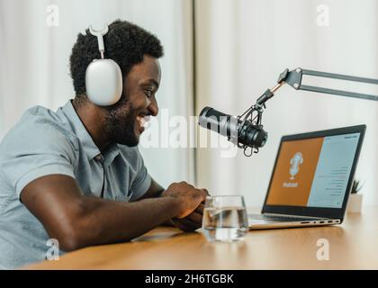 Smiling black man using laptop and recording podcast Stock Photo