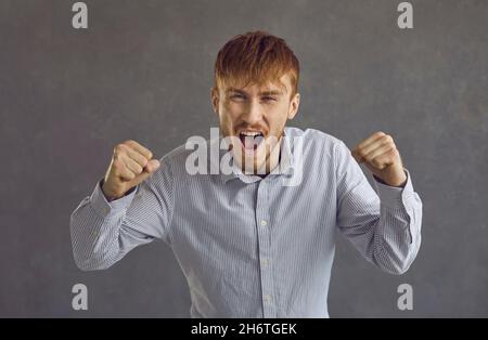 Shouting angry man raging quarreling studio headshot portrait on grey background Stock Photo