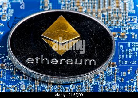 Shining silver metal ETH Ethereum coin on computer mother board Stock Photo