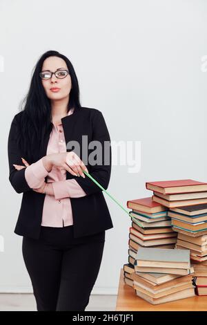 a woman brunette in a business suit teacher with stacks of books Stock Photo