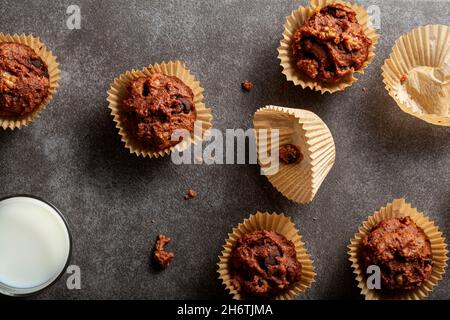 Top view image showing fresh baked cup cakes in paper liners on stone background. Served with a glass of milk for breakfast or snack. Cacoa, fruit and Stock Photo