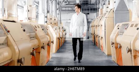 Operator of automatic modern mill for production of flour from wheat and cereals. Stock Photo