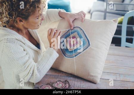Woman at home doing knit work or crochet on a white pillow to decorate and produce decorations. Female people at home busy with hobby and indoor leisu Stock Photo