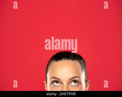 half portrait of a young woman looking up on red background Stock Photo