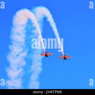 Wing walkers with two biplanes at airshow with blue sky and white smoke Stock Photo