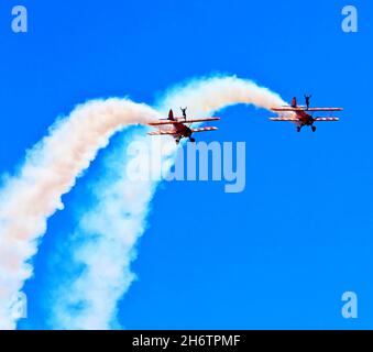 Wing walkers with two biplanes at airshow with blue sky and white smoke Stock Photo