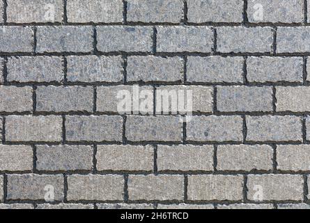 The background and texture of the wall is tiled with rectangular stone tiles with ragged edges on a sunny day. Stock Photo
