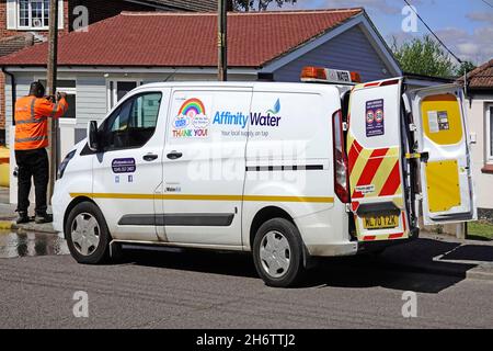 Side view & back doors open on Affinity Water board supply company business Ford van in road street man checks hydrants water flow in Essex England UK Stock Photo