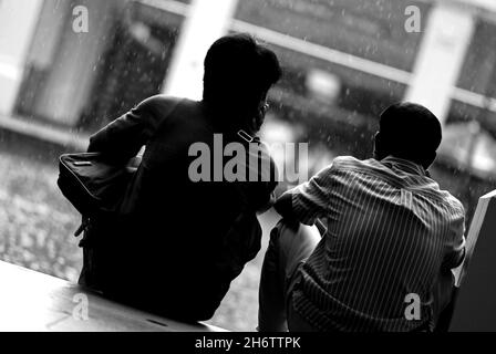 Greyscale back view of two males sitting on the floor Stock Photo