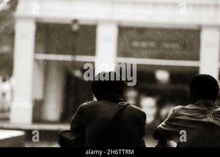 Greyscale back view of two passengers sitting on the floor Stock Photo