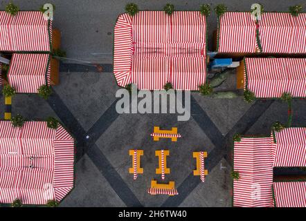 Leipzig, Germany. 18th Nov, 2021. Empty tables stand in empty aisles at a snack bar at the still-closed Leipzig Christmas Market. The market is to take place despite the current Corona situation, but there is to be no serving of alcohol. The mulled wine ban is intended to prevent uncontrolled, hour-long gatherings of people. (Aerial view with a drone) Credit: Jan Woitas/dpa-Zentralbild/dpa/Alamy Live News Stock Photo