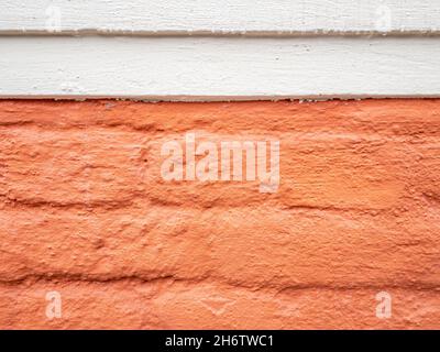Stockholm, Sweden - April 22, 2021: Orange painted brick wall with white upper stripe on cloudy day with negative space Stock Photo