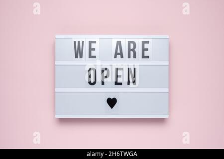 Lightbox with the text WE ARE OPEN on pastel pink background. Minimal concept. Stock Photo