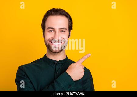 Photo of charming cute young man wear smart casual outfit pointing finger empty space smiling isolated yellow color background Stock Photo
