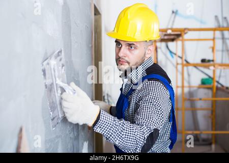 Professional in the helmet is plastering the wall Stock Photo