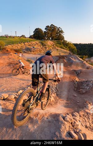 A young mountain bike rider going over the crest of a steep drop, hill at Jubilee Oval bike park in Wahroonga, Sydney, New South Wales, Australia Stock Photo
