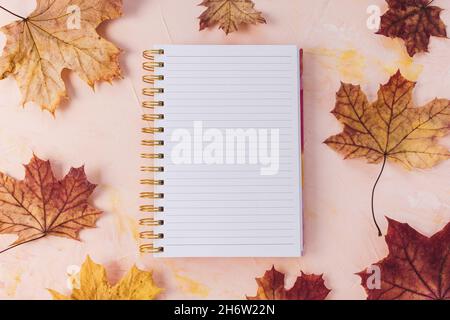 Open notepad mockup and fall maple leaves, pastel pink background, woman desk workspace. Autumn lifestyle concept. To Do List template, empty page, template. Minimalist flat lay, top view, copy space Stock Photo