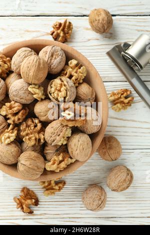 Nutcracker and bowl of walnuts on white wooden background Stock Photo