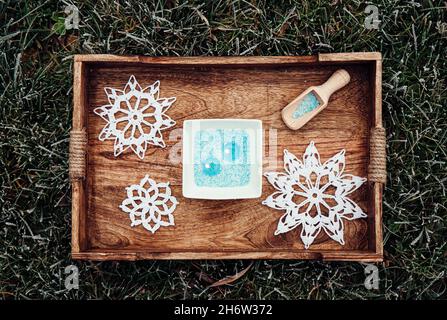 Blue and white granulated wax crystals to create candles by pouring in bowl and inserting wick. Handmade sand candle in white ceramic bowl on wood. Stock Photo