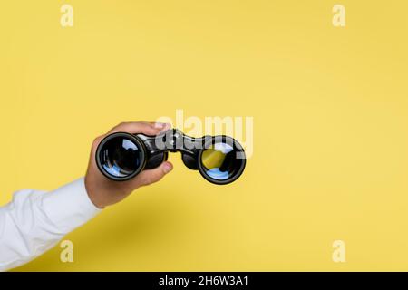 cropped view of man holding binoculars on yellow Stock Photo