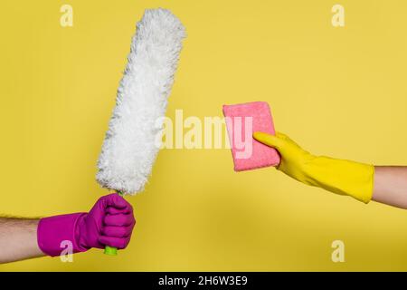 cropped view of man and woman in rubber gloves holding cleaning supplies on yellow Stock Photo