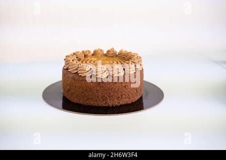Delicious chocolate and caramel cake on black plate, white background. Stock Photo
