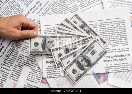 KYIV, UKRAINE - NOVEMBER 1, 2021: partial view of man holding dollar banknote near printed newspapers Stock Photo