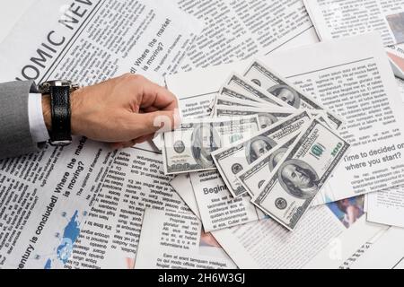 KYIV, UKRAINE - NOVEMBER 1, 2021: cropped view of man holding dollar banknote near printed newspapers Stock Photo