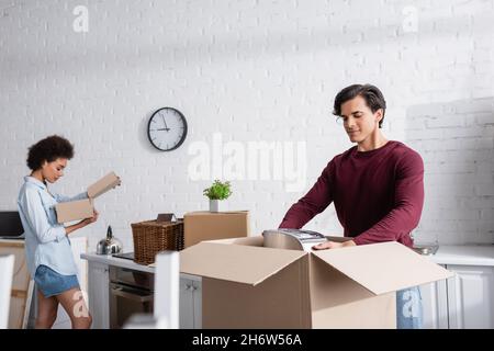 young man unpacking box near african american girlfriend Stock Photo