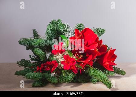 Large and beautiful winter bouquet with amaryllis, fir branches, alstroemeria Tstands against a white wall. Stock Photo