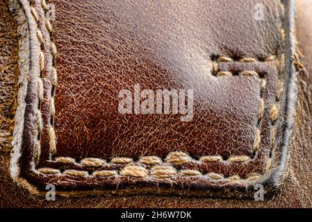 Macro background made of brown natural leather with white stitches all around. Stock Photo