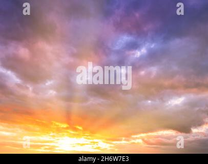 Dramatic cloudy sky at sunset or sunrise. The sun's rays breaking through the clouds. Stock Photo