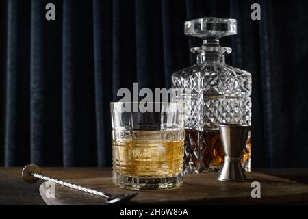 Whiskey in rocks and bottle on dark blue curtain background. Holiday party. Stock Photo