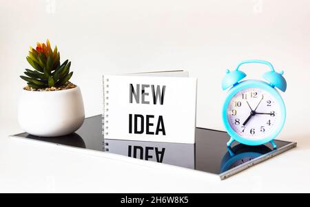 Notepad with the text new idea on a beautiful black and white background with a clock and a cactus flower. Stock Photo