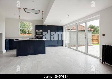 Wratting, England - August 19 2019: Refitted traditional looking kitchen with built in appliances, peninsula and bifold doors to patio outside Stock Photo