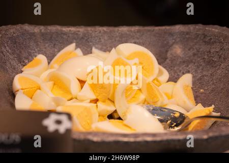 Salad buffet in the restaurant. Bowl with pieces of hard-boiled eggs.  Stock Photo