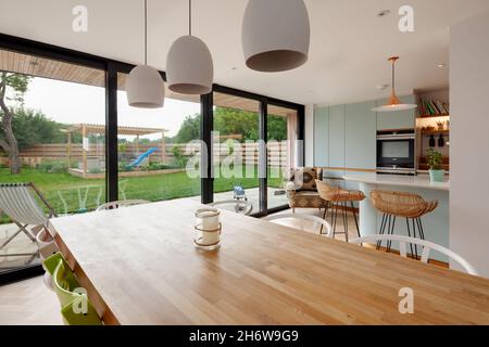 Dry Drayton, England - August 2 2019: Contemporary dining area looking over the table towards the breakfast bar and beyond through the patio doors Stock Photo